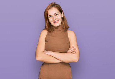 Sıradan kıyafetler giyen, kollarını kavuşturup kameraya gülümseyen beyaz bir kadın. pozitif kişi. 