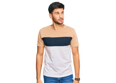 Gündelik kıyafetler giyen genç yakışıklı adam gülümseyerek yan tarafa bakıyor ve düşünüyor.. 