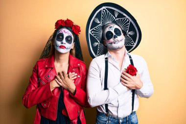 Sarı üzerine ölü kostümün giyildiği gün göğsünde elleri kapalı, yüzünde minnet dolu bir jest olan çift. sağlık kavramı. 