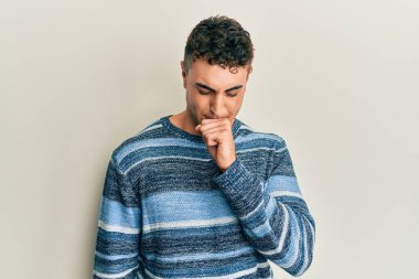 Günlük kazak giyen İspanyol genç adam kendini iyi hissetmiyor ve soğuk algınlığı veya bronşitin belirtisi olarak öksürüyor. sağlık hizmeti kavramı. 