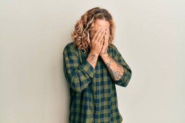 Sakallı, uzun saçlı, sıradan kıyafetler giyen, suratını ellerle örten ve ağlayan yakışıklı bir adam. depresyon kavramı. 