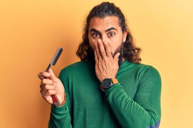 Genç Arap adam berber jiletini tutarak ağzını eliyle kapadı, şok oldu ve hata yapmaktan korktu. şaşırmış ifade 