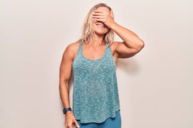 Orta yaşlı beyaz kadın spor kıyafetleri giyiyor, gülümsüyor ve elleri yüzünde, şaşırtmak için gözlerini kapatıyor. kör kavram. 