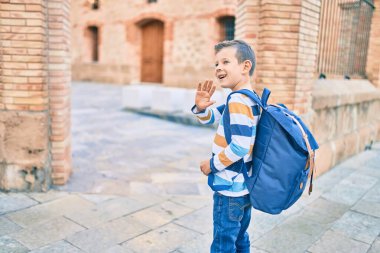 Sevimli beyaz çocuk gülümseyerek okulda el ele vedalaşıyor..