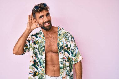 Yaz kıyafetleri giymiş genç İspanyol bir adam kamerayı işaret ediyor ve kendine güvenen bir jest, ciddi görünüyor. 