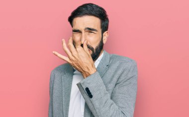 Genç İspanyol bir adam iş kıyafetleri giyip pis ve iğrenç bir koku alıyor. Nefesini burnunda tutuyor. Kötü kokuyor. 