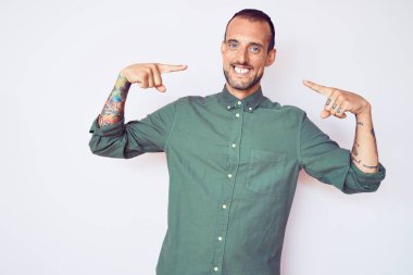 Dövmeli, sıradan kıyafetler giyen, kendine güvenen, gülümseyen, kendini gururlu ve mutlu gösteren genç yakışıklı bir adam.. 