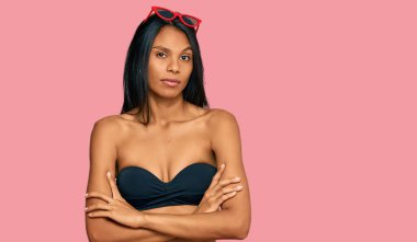 Genç Afro-Amerikalı kadın, bikinili, kuşkucu ve gergin. Yüzünde çapraz kollu tasvip etmeyen bir ifade var. negatif kişi. 