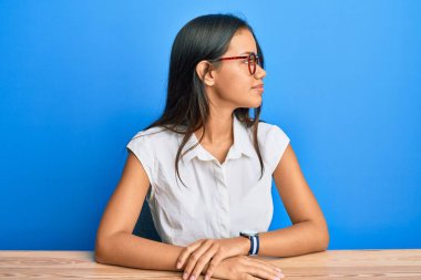 Güzel İspanyol kadın gündelik giysiler giyip masaya oturuyor. Yan tarafa bakıyor, profil pozu veriyor. Doğal bir yüzü ve kendine güvenen bir gülümsemesi var.. 