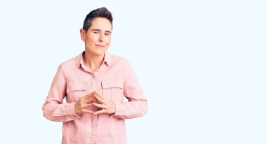 Kısa saçlı, günlük giysiler giyen, el ele tutuşan, gülümseyen, rahat ve neşeli genç bir kadın. Başarı ve iyimserlik 