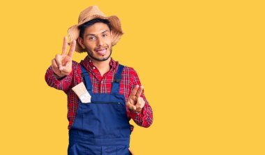 Yakışıklı Latin Amerikalı genç adam becerikli üniformasını giyiyor. Dili dışarı fırlamış gülümsüyor ve iki elini de zafer işareti yapıyor. İki numara.. 