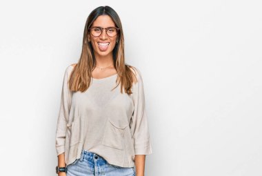 Günlük kıyafetler giyen ve gözlük takan genç bir kadın komik bir ifadeyle dilini dışarı çıkartıyor. duygu kavramı. 