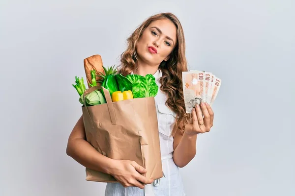 Joven Chica Rubia Sosteniendo Bolsa Papel Con Comestibles Libras Mirando —  Fotos de Stock