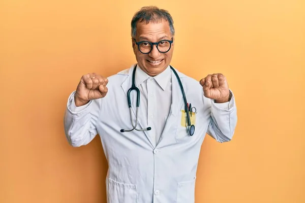 医者のコートと聴診器を身に着けている中世のインド人男性は驚きと腕を上げて開いて目で成功のために驚いています 勝者のコンセプト — ストック写真