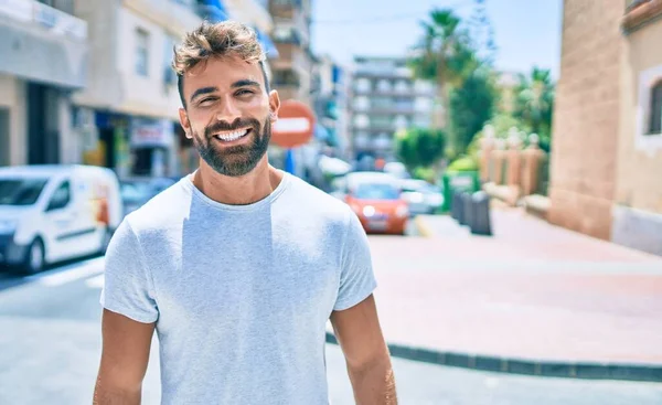 Genç İspanyol adam gülümseyerek şehirde mutlu bir şekilde yürüyor.