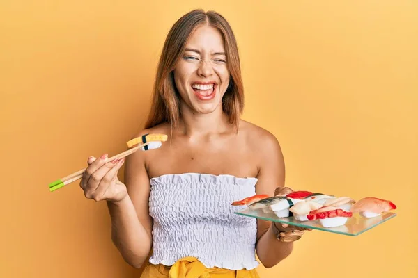 Beautiful Young Blonde Woman Eating Omelette Sushi Using Chopsticks Winking — Stock Photo, Image
