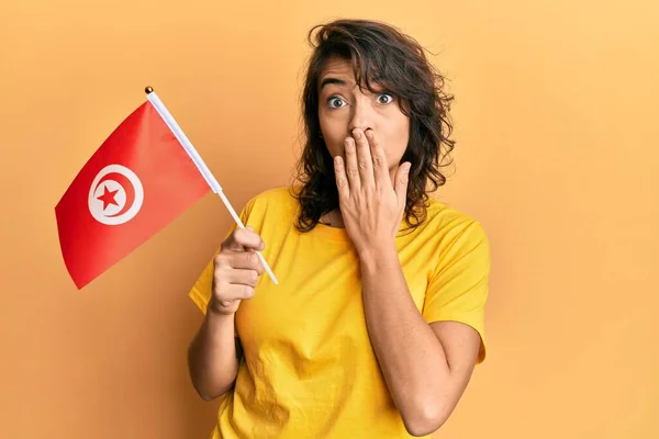 Mujer Hispana Joven Sosteniendo Bandera Tunisia Cubriendo Boca Con Mano —  Fotos de Stock