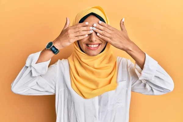 伝統的なイスラムのヒジャーブスカーフを身に着けている若いブルネットのアラブ女性は陽気で面白い手で目をカバーしています 視覚障害の概念 — ストック写真