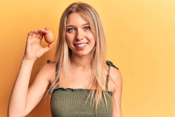 Yumurta Tutan Genç Sarışın Kadın Pozitif Mutlu Görünüyor Dişlerini Gösteren — Stok fotoğraf