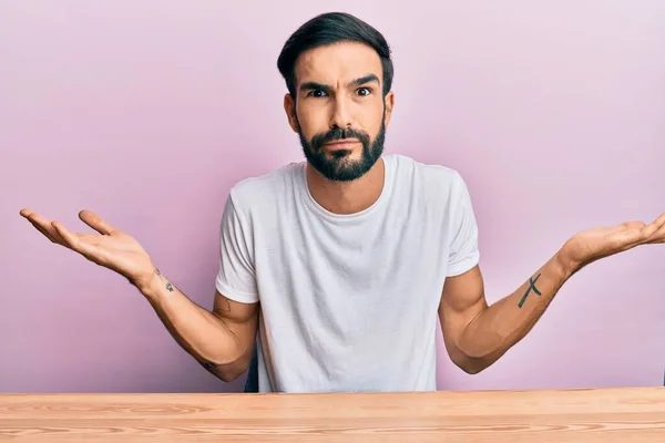 Jovem Hispânico Vestindo Roupas Casuais Sentado Mesa Sem Noção Confuso — Fotografia de Stock