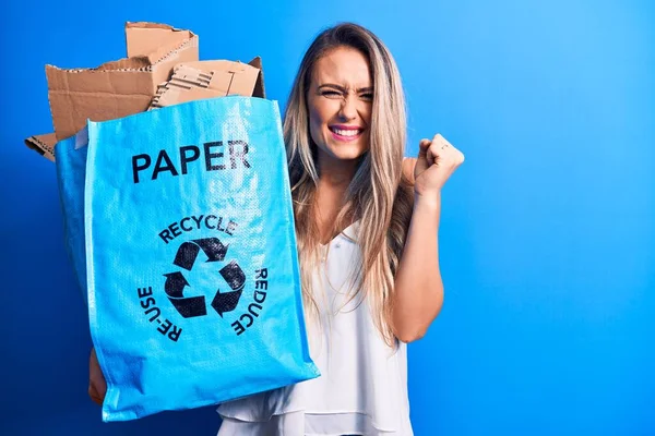 若いです美しいですブロンド女性リサイクル保持紙リサイクルバッグフルの紙の悲鳴誇り 勝利と成功を祝います非常に興奮して上げ腕 — ストック写真