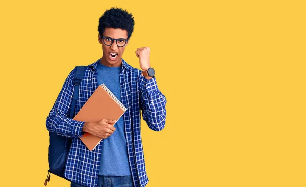 Young African American Man Wearing Student Backpack Holding Book Angry — Stock Photo, Image