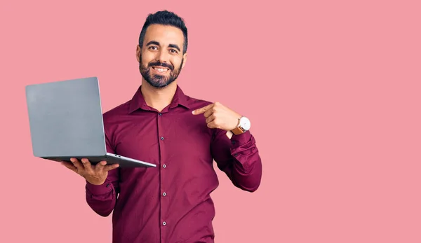 Jovem Hispânico Homem Segurando Laptop Apontando Dedo Para Auto Sorrindo — Fotografia de Stock