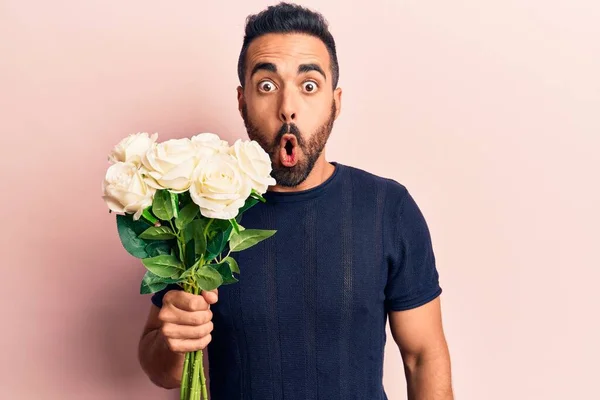 Jovem Hispânico Homem Segurando Flores Assustado Espantado Com Boca Aberta — Fotografia de Stock