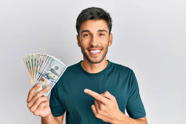 Jovem Homem Bonito Segurando Dólares Sorrindo Feliz Apontando Com Mão — Fotografia de Stock