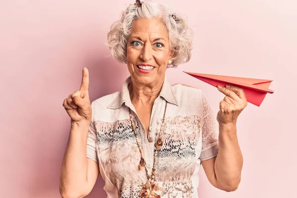 Senior Grauhaarige Frau Mit Papierflugzeug Lächelnd Mit Einer Idee Oder — Stockfoto