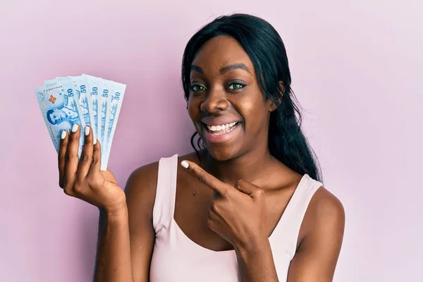 Joven Mujer Afroamericana Sosteniendo Billetes Tailandeses Baht Sonriendo Feliz Señalando — Foto de Stock