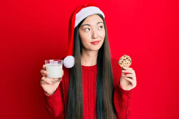 Jovem Chinesa Usando Chapéu Natal Segurando Biscoitos Leite Sorrindo Olhando — Fotografia de Stock