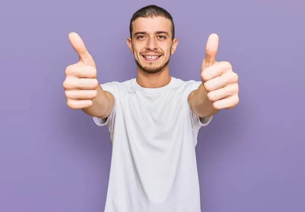 白人のカジュアルなシャツを着たヒスパニック系の若者は 手で積極的なジェスチャーを行うことを承認します 親指アップ笑顔と成功のために幸せ 勝者のジェスチャー — ストック写真