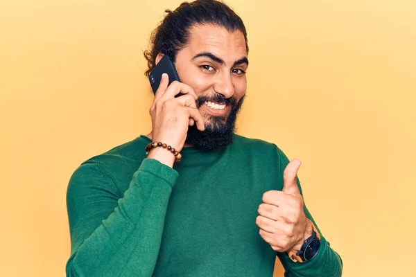 スマートフォンで話している会話をしている若いアラブ人男性笑顔と正 親指アップ優れた承認サインを行う — ストック写真