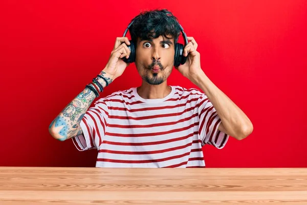 Junger Hispanischer Mann Sitzt Mit Kopfhörern Auf Dem Tisch Und — Stockfoto