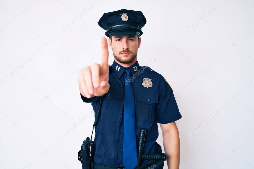 Young caucasian man wearing police uniform pointing with finger up and angry expression, showing no gesture 