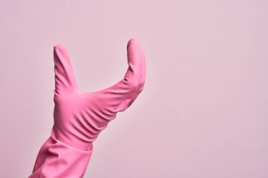 İzole edilmiş pembe arka plan üzerinde temizlik eldiveni olan beyaz bir adamın eli. Görünmez bir şeyi alıp, parmaklarında boşluk gösteren bir nesneyi tutuyor.