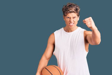 Basketbol topu tutan yakışıklı genç adam öfkeyle bağırıyor, öfkeyle bağırıyor ve el kaldırıyor. 