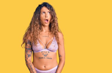 Dövmeli genç İspanyol kadın şok olmuş yüzüne iç çamaşırı giymiş, şüpheci ve alaycı görünüyor, ağzı açık kalınca şaşırıyor. 