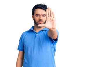 Günlük kıyafetler giyen genç İspanyol adam avucunun içi gibi şarkı söylemeyi kesiyor. Yüzünde olumsuz ve ciddi bir jest olan uyarı ifadesi. 