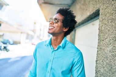 Genç, yakışıklı, Afro-Amerikan bir adam. Günlük kıyafetler ve güneş gözlüğü takıyor. Mutlu gülümsüyor. Yüzünde tebessümle kasaba caddesinde yürürken yan tarafa bakıyor..