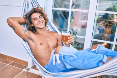 Genç İspanyol adam terasta hamakta uzanmış bira içerek rahatladı..