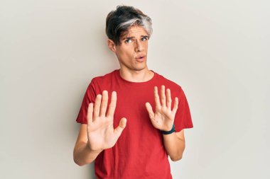 Latin asıllı genç bir adam, sıradan kıyafetler giyip avuçlarını hareket ettiriyor. Korkmuş ve iğrenç bir ifadeyle reddediyor. Dur ve yasakla. 