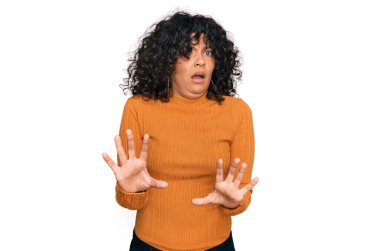 Günlük kıyafetler giyen genç İspanyol kadın korku ifadesinden korkuyor ve dehşete düşüyor. El hareketlerini durdur, şok içinde bağır. panik konsepti. 