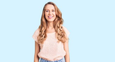 Sarı saçlı, sıradan kıyafetler giyen, mutlu ve havalı bir gülüşü olan güzel beyaz bir kadın. şanslı kişi. 