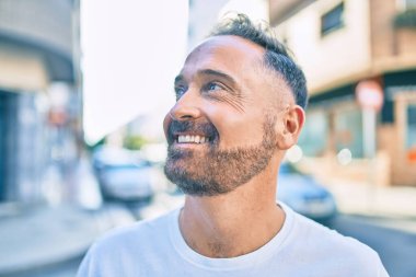 Orta yaşlı, yakışıklı, gülümseyen, mutlu, şehre bakan bir adam..