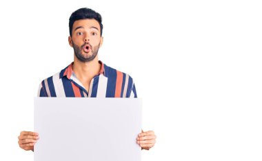 Genç, yakışıklı İspanyol adam elinde boş alanlı mukavva pankart tutuyor. Şaşırmak için ağzı açık ve korkmuş, inançsız bir yüz. 