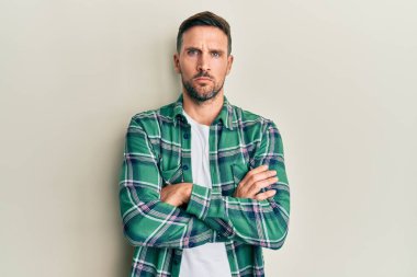 Sıradan kıyafetler giyen, kuşkucu ve gergin sakallı yakışıklı bir adam. Yüzünde çapraz kollu tasvip etmeyen bir ifade. negatif kişi. 