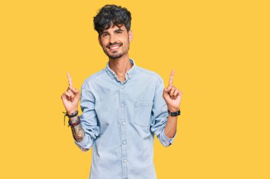 Gündelik kıyafetler giyen, kendine güvenen, parmaklarını farklı yönlere çeviren genç İspanyol adam. reklam için kopyalama alanı 