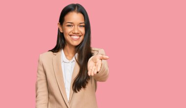 İş ceketi giymiş güzel İspanyol bir kadın dostça bir şekilde el sıkışarak selamlıyor ve selamlıyor. başarılı iş. 